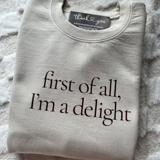 A gray sweatshirt with the text 'first of all, I'm a delight' printed in the center.